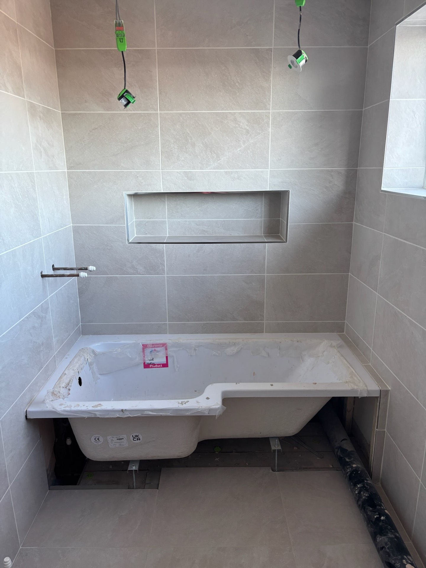 Grey tiled bathroom with recessed shelf and fitted bath