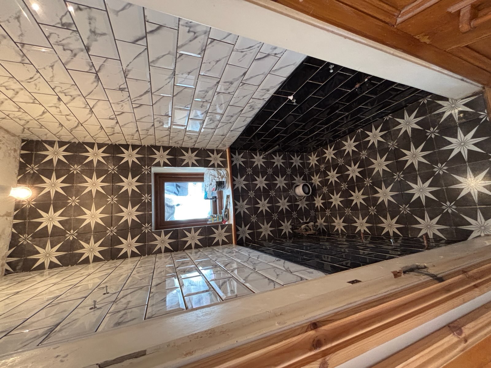 Black and white star patterned tiling in a narrow bathroom