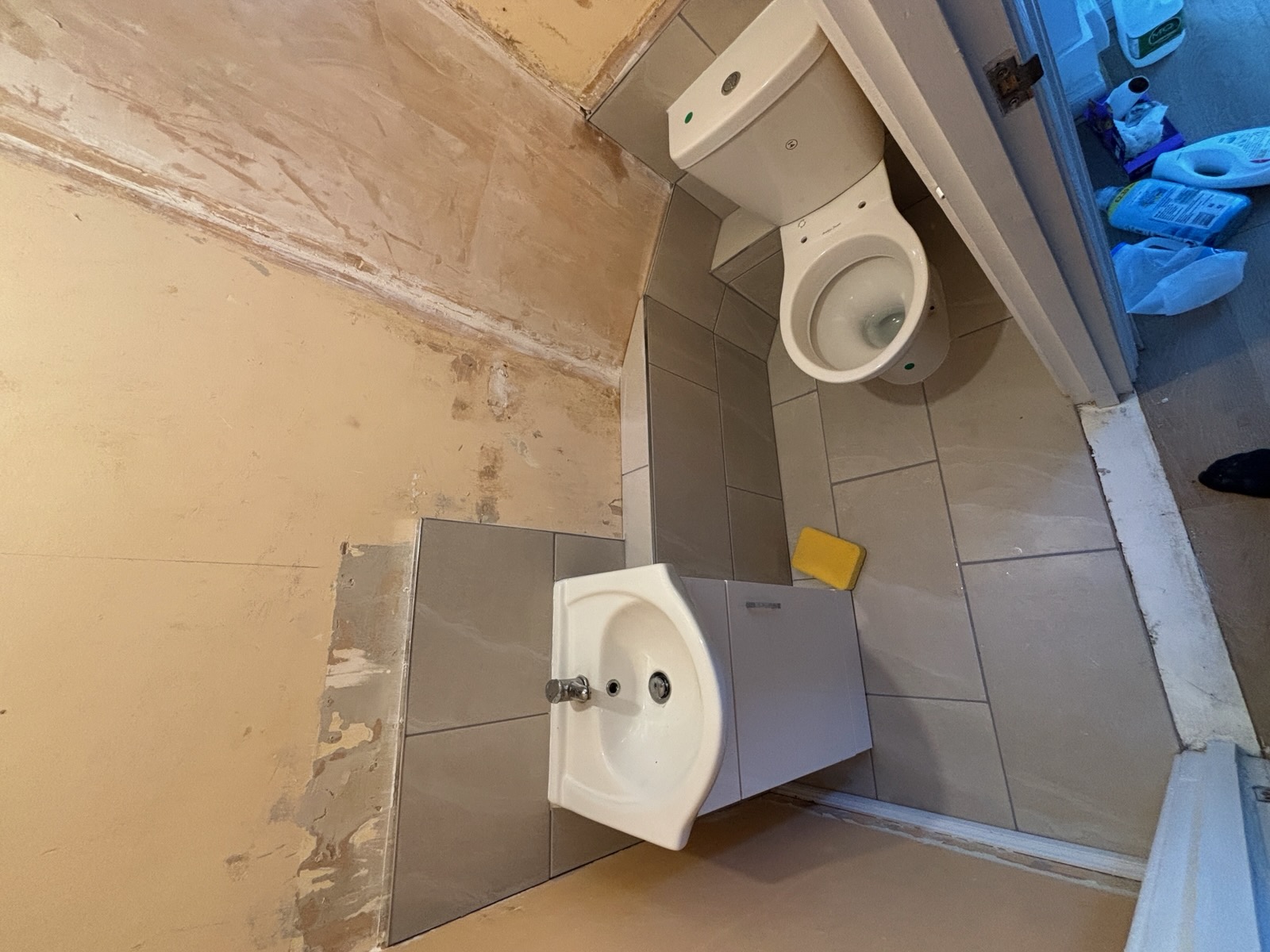 Compact cloakroom with newly fitted grey floor and wall tiles